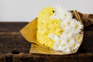 A yellow and white bouquet of flowers wrapped in a decorative brown paper. The cover image for the Congratulations Collection