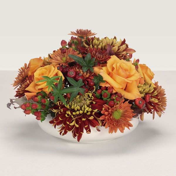 White porcelain harvest centerpiece with red, orange and peach flowers 