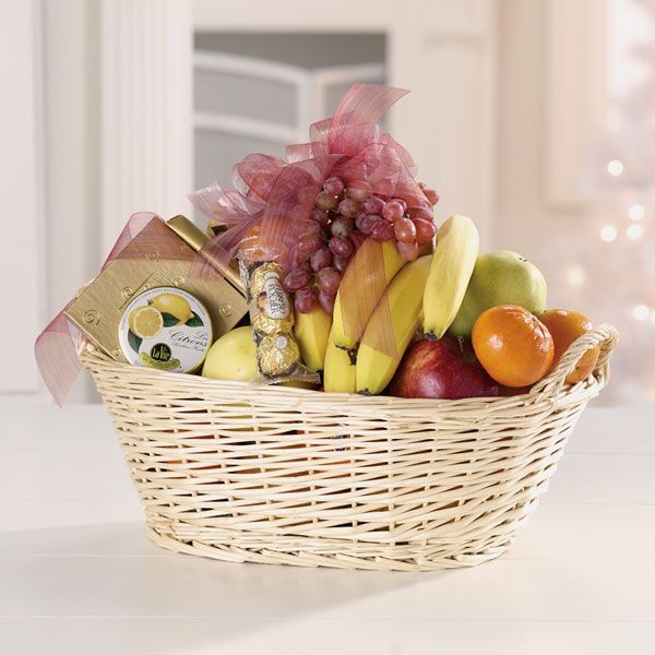 Ribbon-topped straw basket overflowing with an abundance of fruits and treats