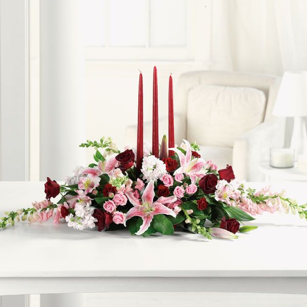 Floral and candle arrangement featuring pink lilies, several shades of roses, snapdragons and other floral favorites