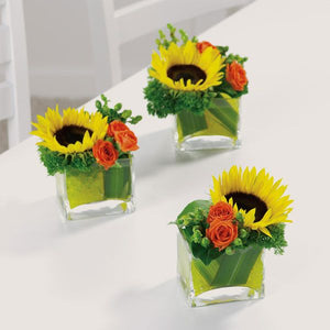 Several breakaway sunflower and spray rose centerpieces in glass vases