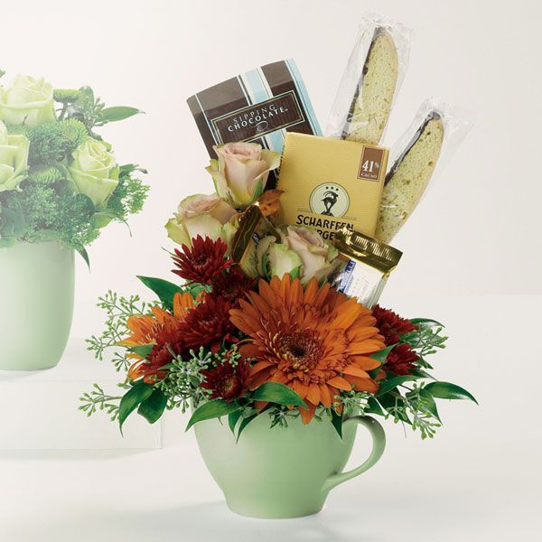 Floral arrangement in a mug with chocolates and biscotti