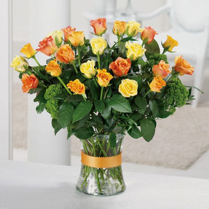 Assortment of yellow and orange roses with a glass vase adorned with Camellia and Italian Ruscus