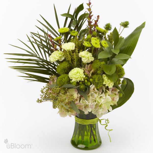 green floral arrangement with eryngium, button pomp oms, brunea, green trick dianthus, carnation, hypericum, and hydrangea in a green vase