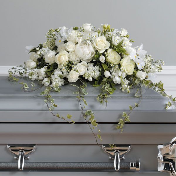 White casket floral arrangement featuring roses, iris, tulips and carnations with ivy.